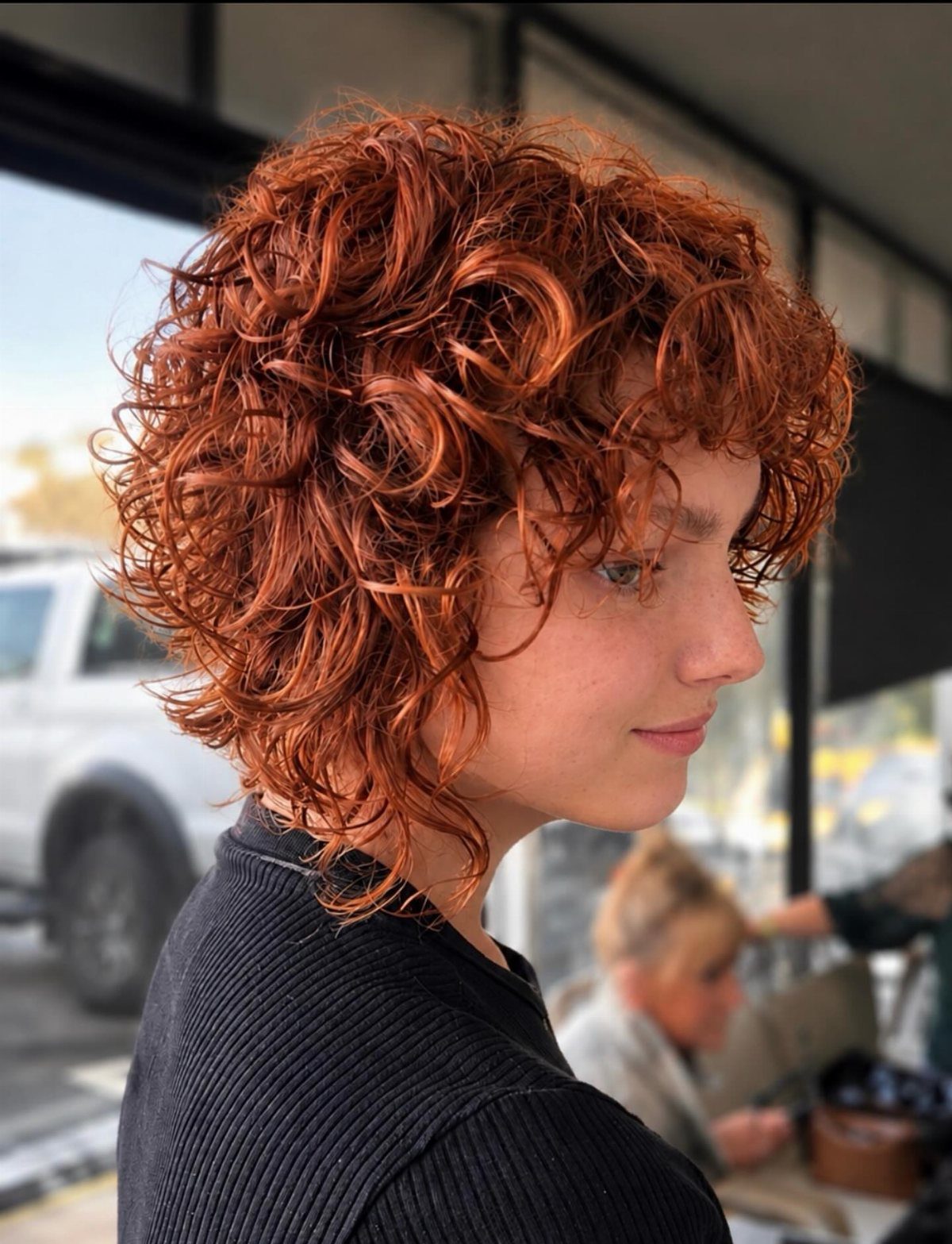 Person with short, curly red hair in a layered wolf cut style.