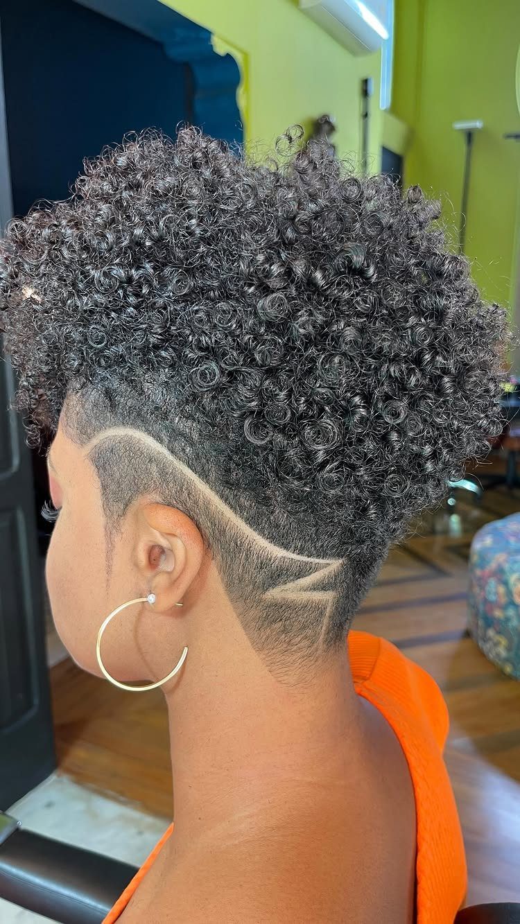 Short tightly coiled black hair with a shaved artistic design on the side.