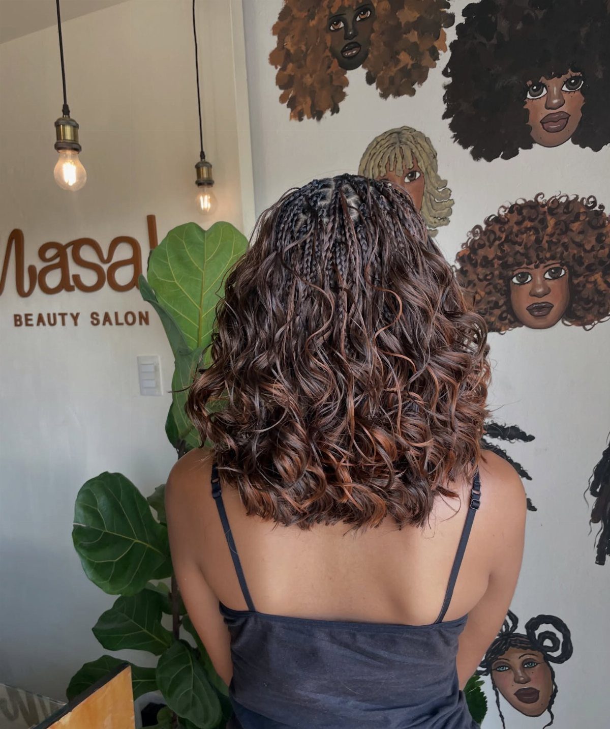 Brown curly hair with small braids at the crown seen from behind.