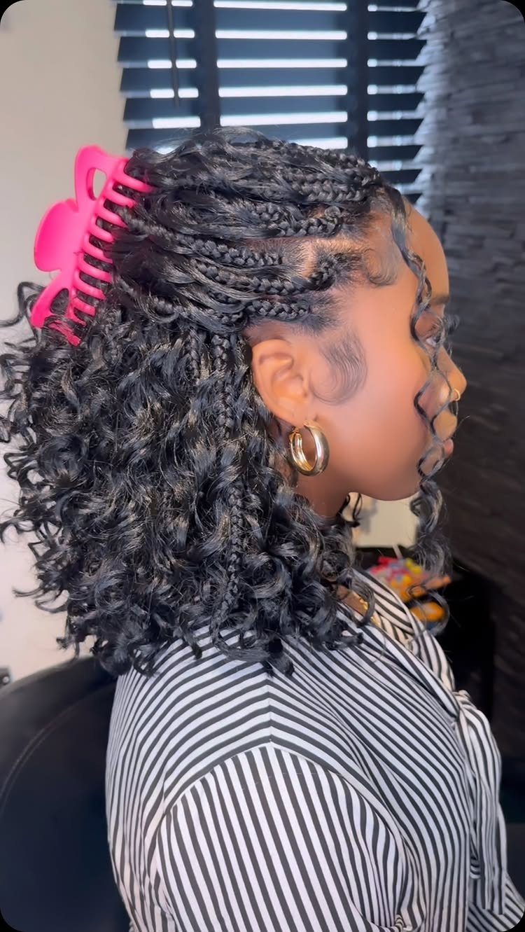 Black hair with small braids and curly ends held by a pink claw clip.