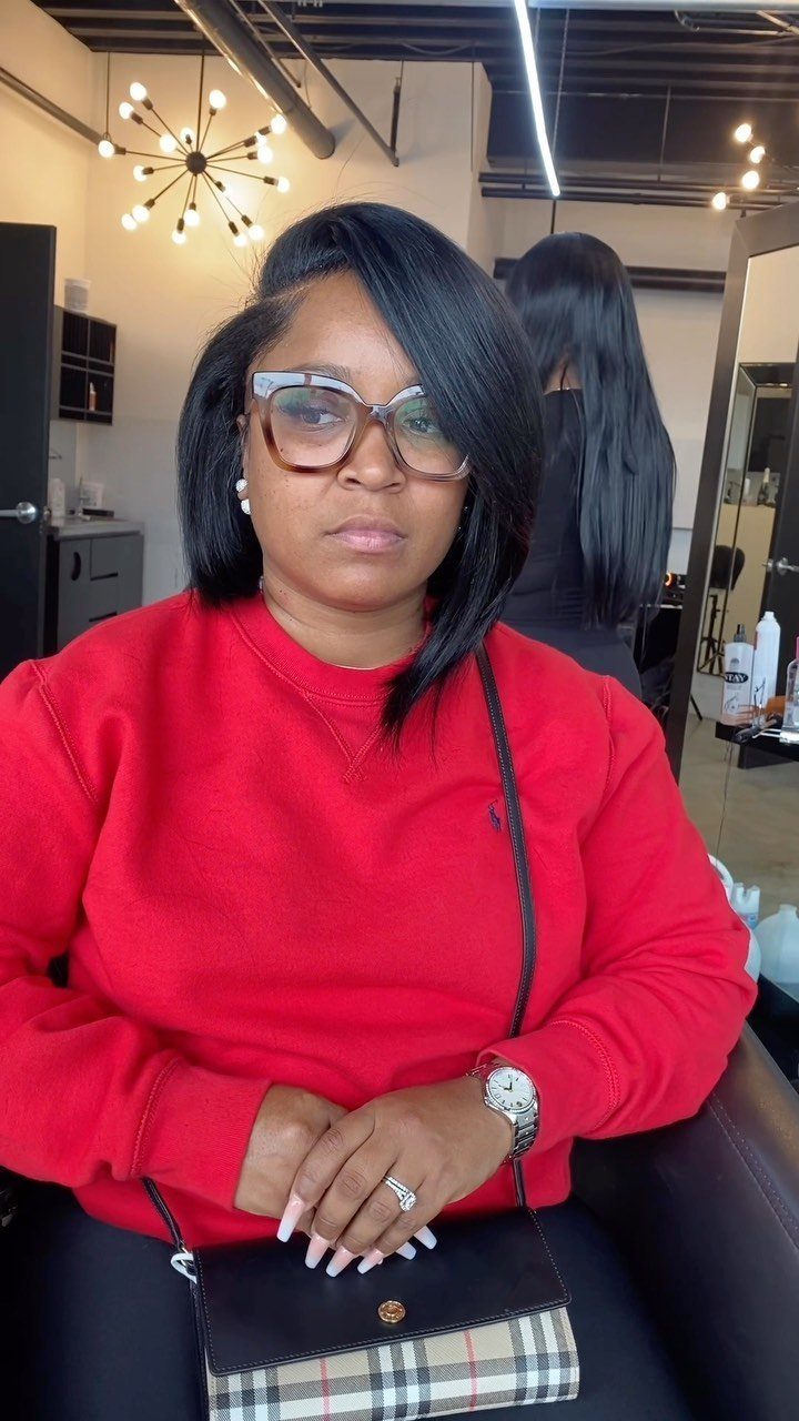 Woman with a deep side part in black hair wearing a red sweatshirt.