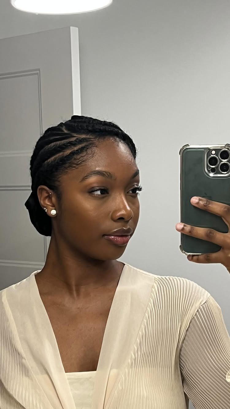 Woman with black hair styled in flat twists against the scalp taking a selfie.