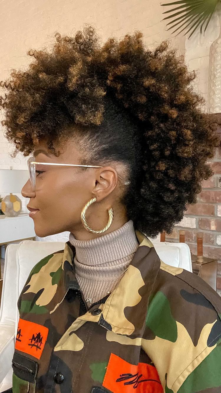 Woman with a frohawk hairstyle featuring voluminous brown curls and pinned sides.