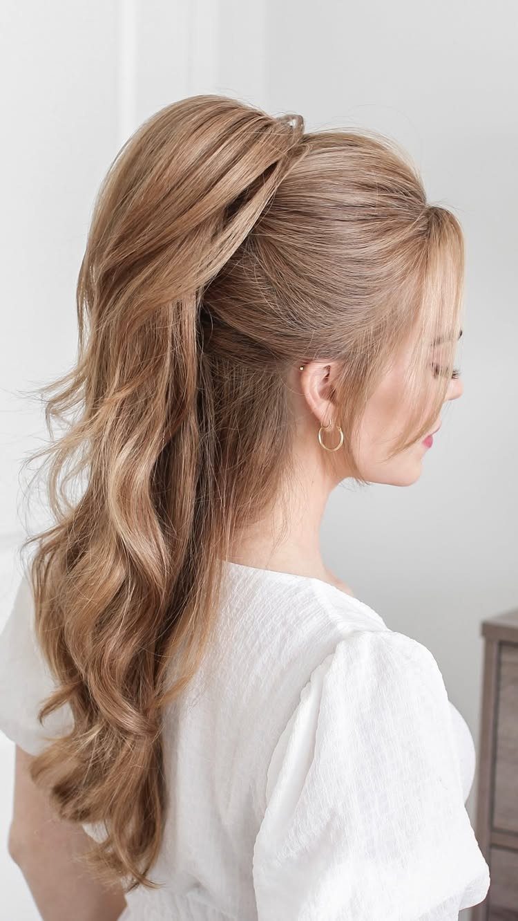 Woman with blonde wavy hair styled in a high half ponytail