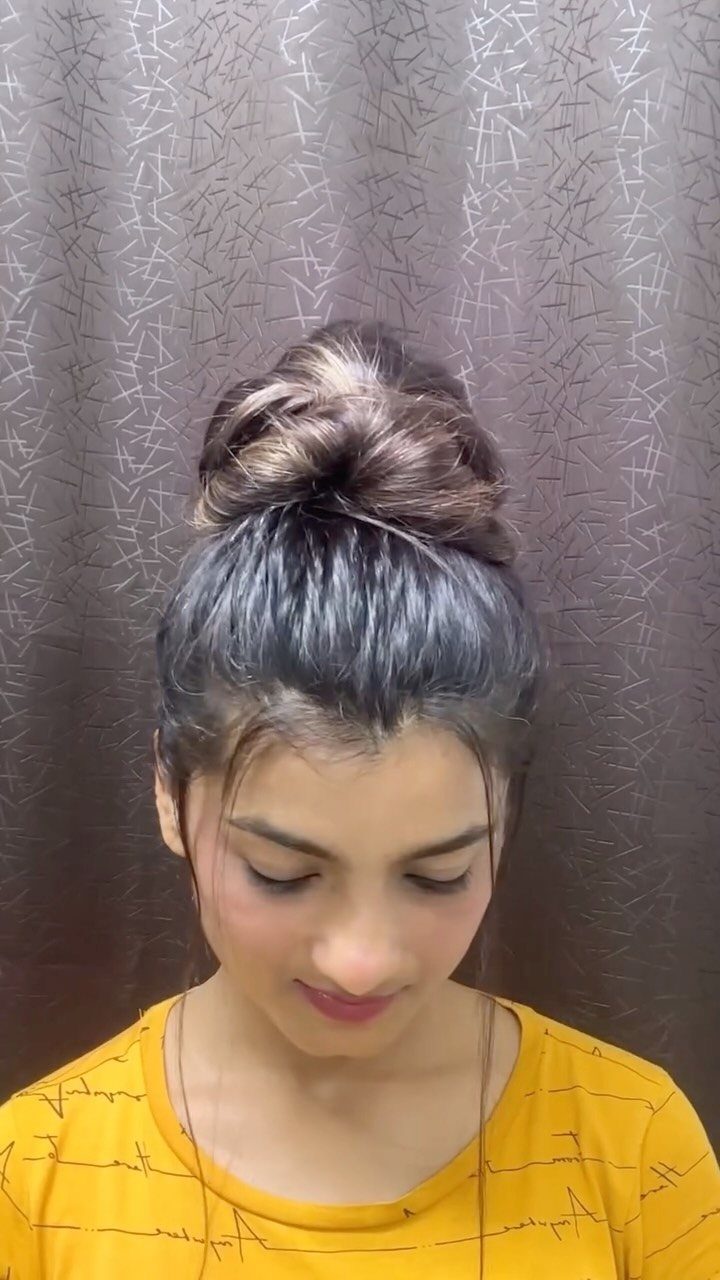 Woman with dark hair styled in a large, twisted high bun.