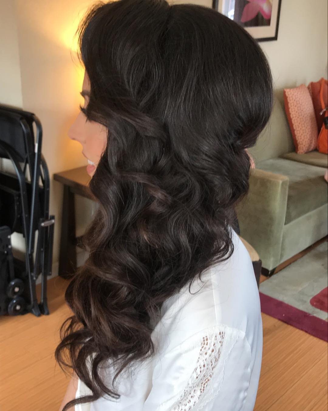 Woman with long dark brown hair styled in voluminous side-swept curls over her shoulder.
