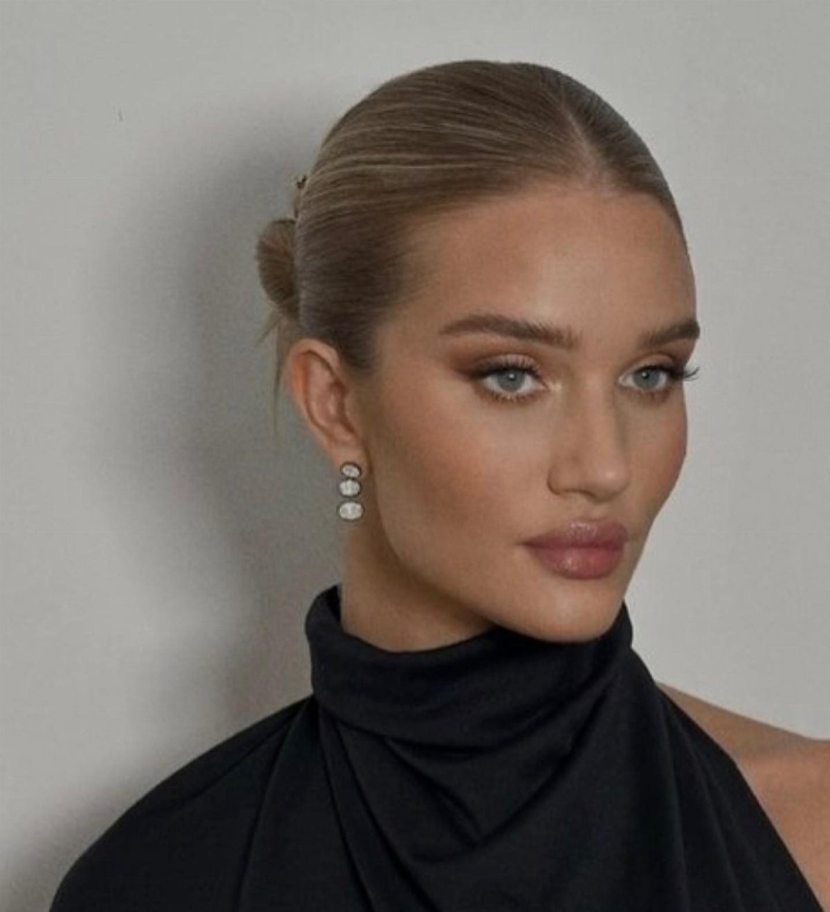 Woman with blonde hair in a sleek slicked-back low bun and middle part.