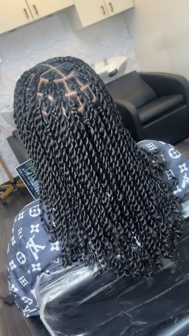 Long black hair styled in two-strand twists from the back in a salon.