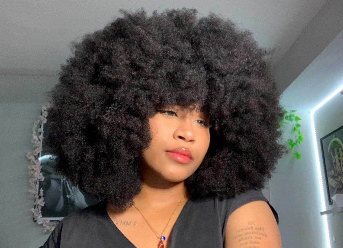 Woman with a large, voluminous black afro hairstyle wearing a black top.