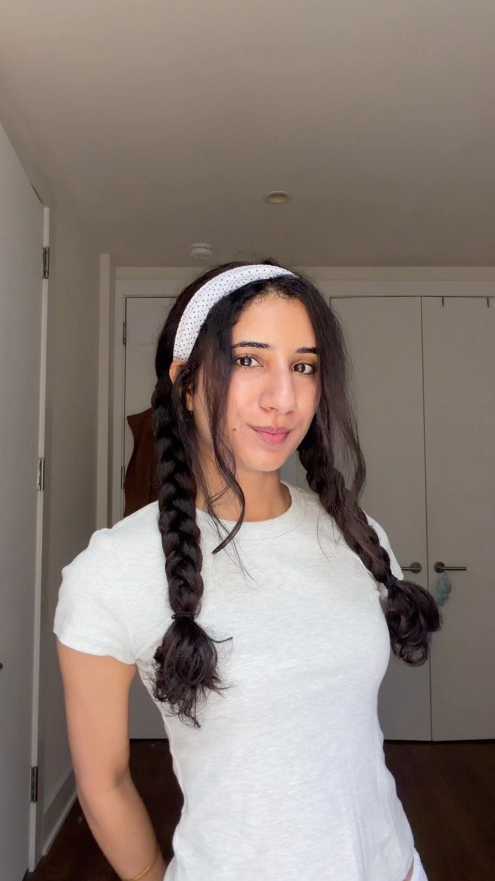 12 Hairstyles to Hide Bangs, From Quick Sweeps to Sleek Buns 12 Woman with braided dark hair wearing a white headband to pull back bangs.