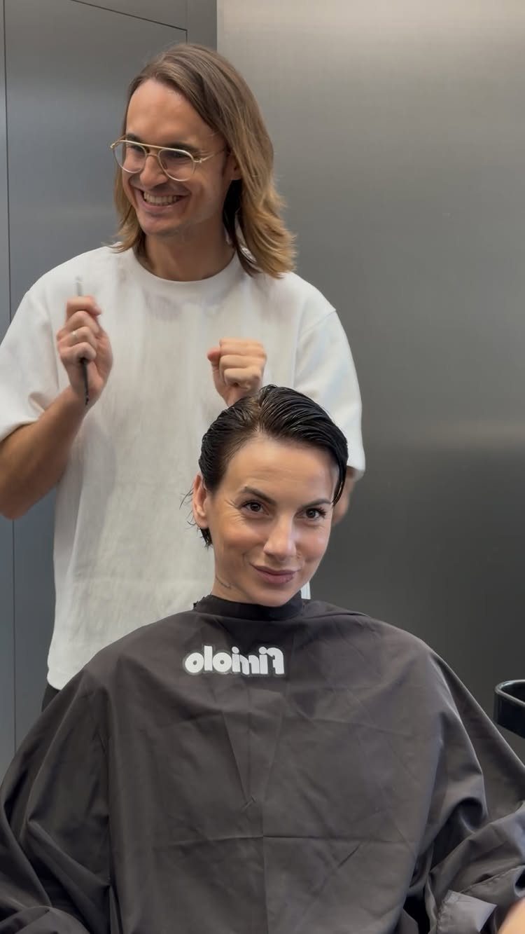 12 Hairstyles to Hide Bangs, From Quick Sweeps to Sleek Buns 4 Woman with dark hair slicked back in a wet look at a salon.
