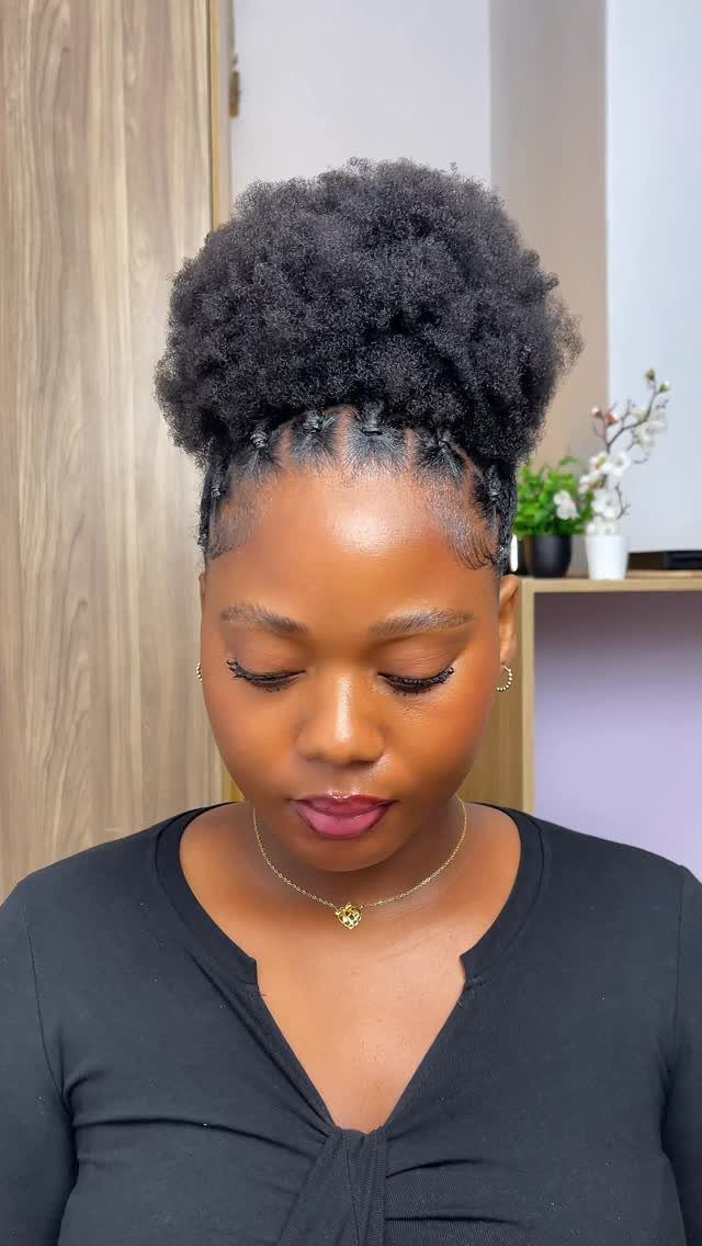 Woman with black hair styled in a high, rounded afro puff updo.