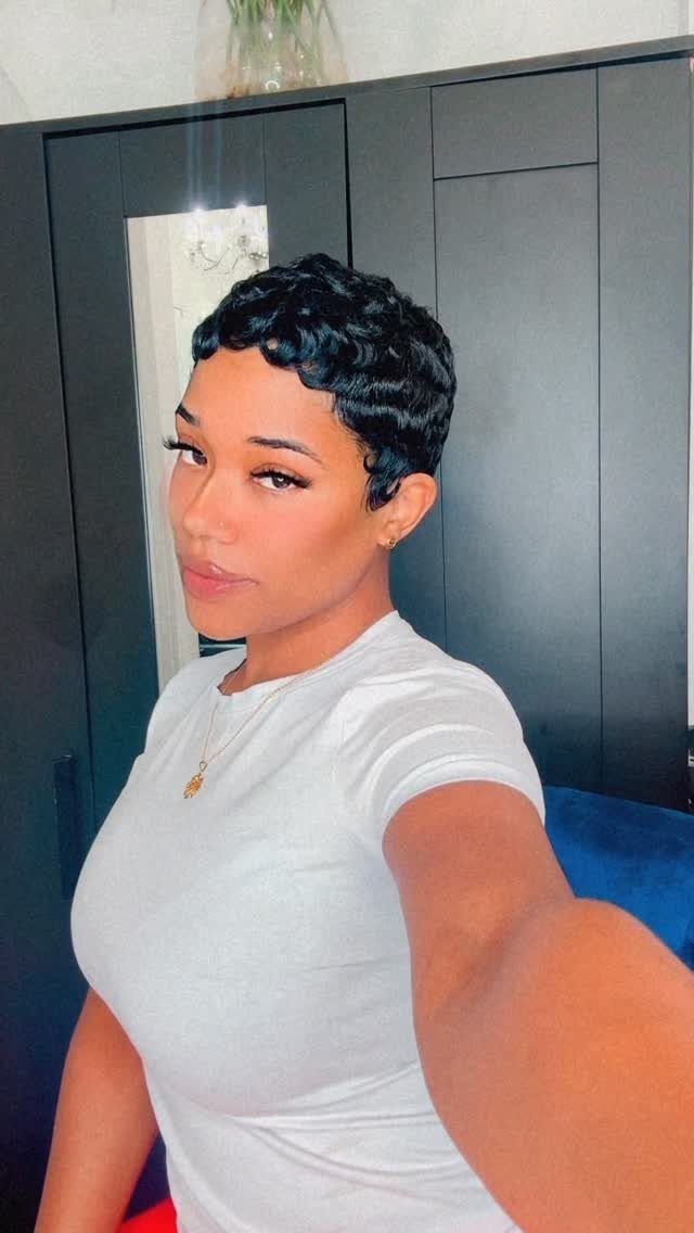 Woman with short black hair styled in glossy, textured gel waves wearing white t-shirt.