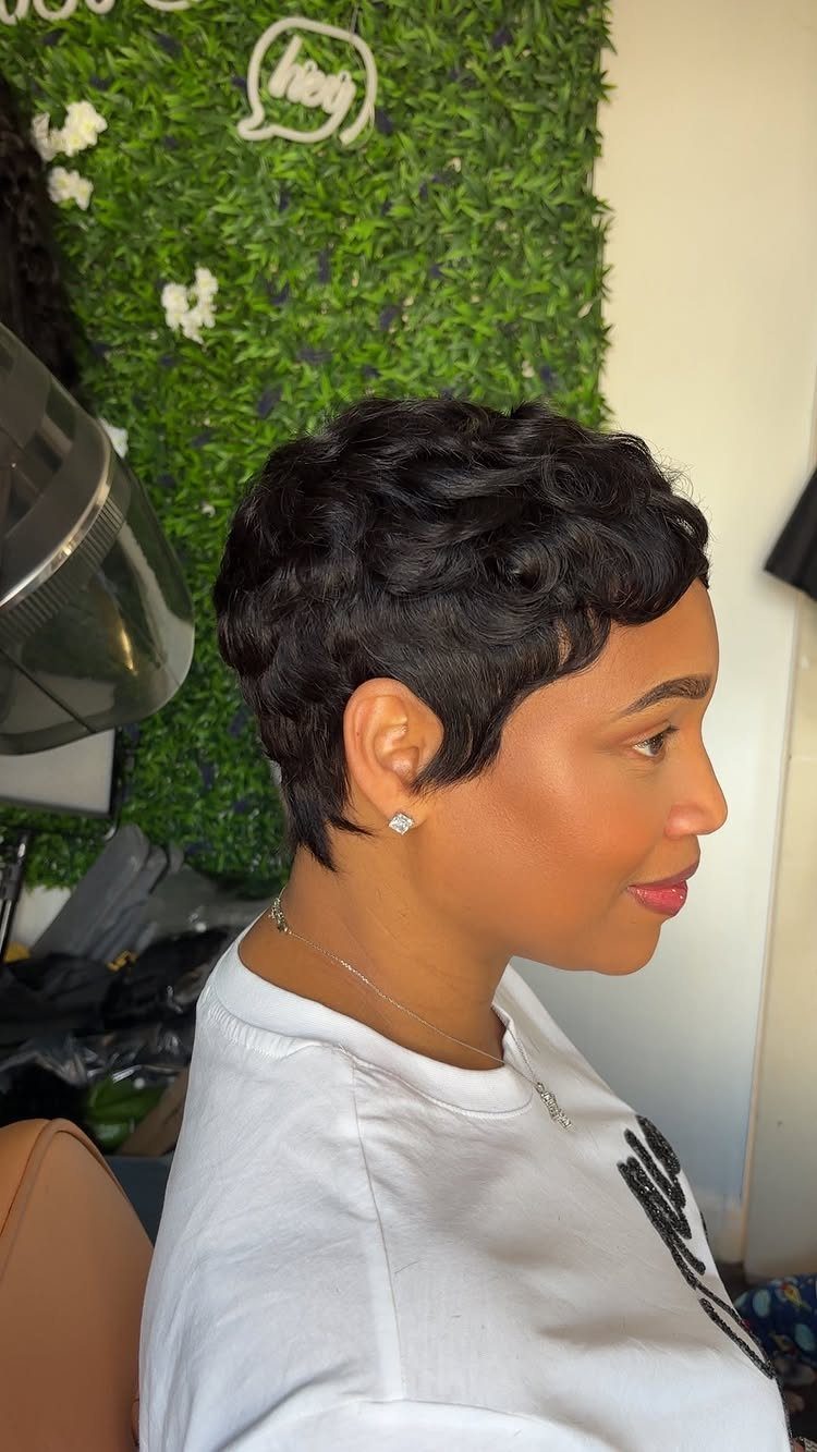 Woman with short curly black hair in a cropped perm cut side profile