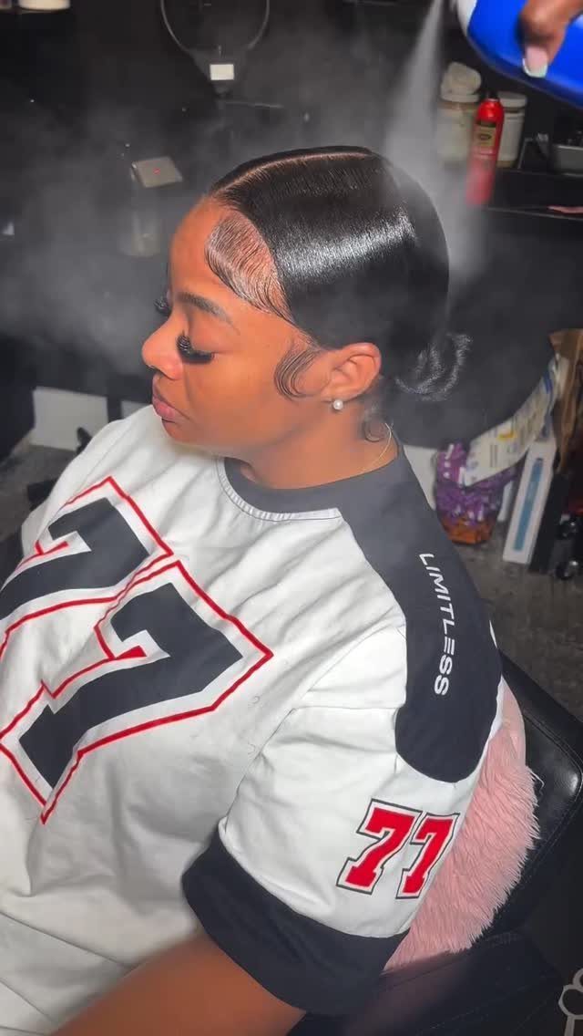 Woman with sleek black hair styled in a polished low ponytail wearing a jersey.