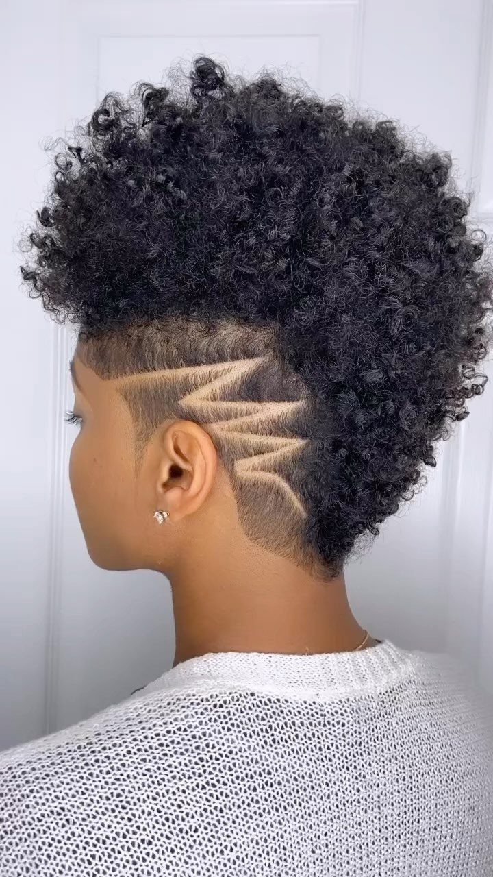 Person with curly black hair, textured top and geometric shaved patterns on the side.