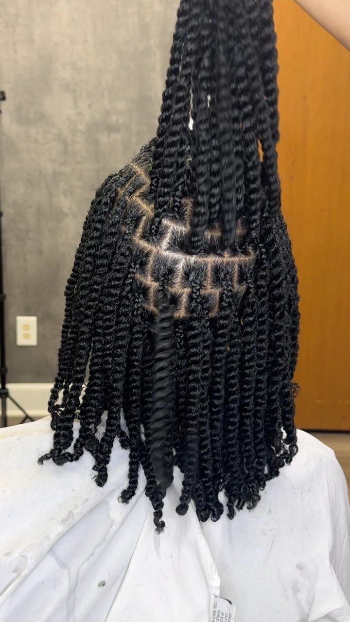 Black hair styled in two-strand twists, with some sections lifted upwards.
