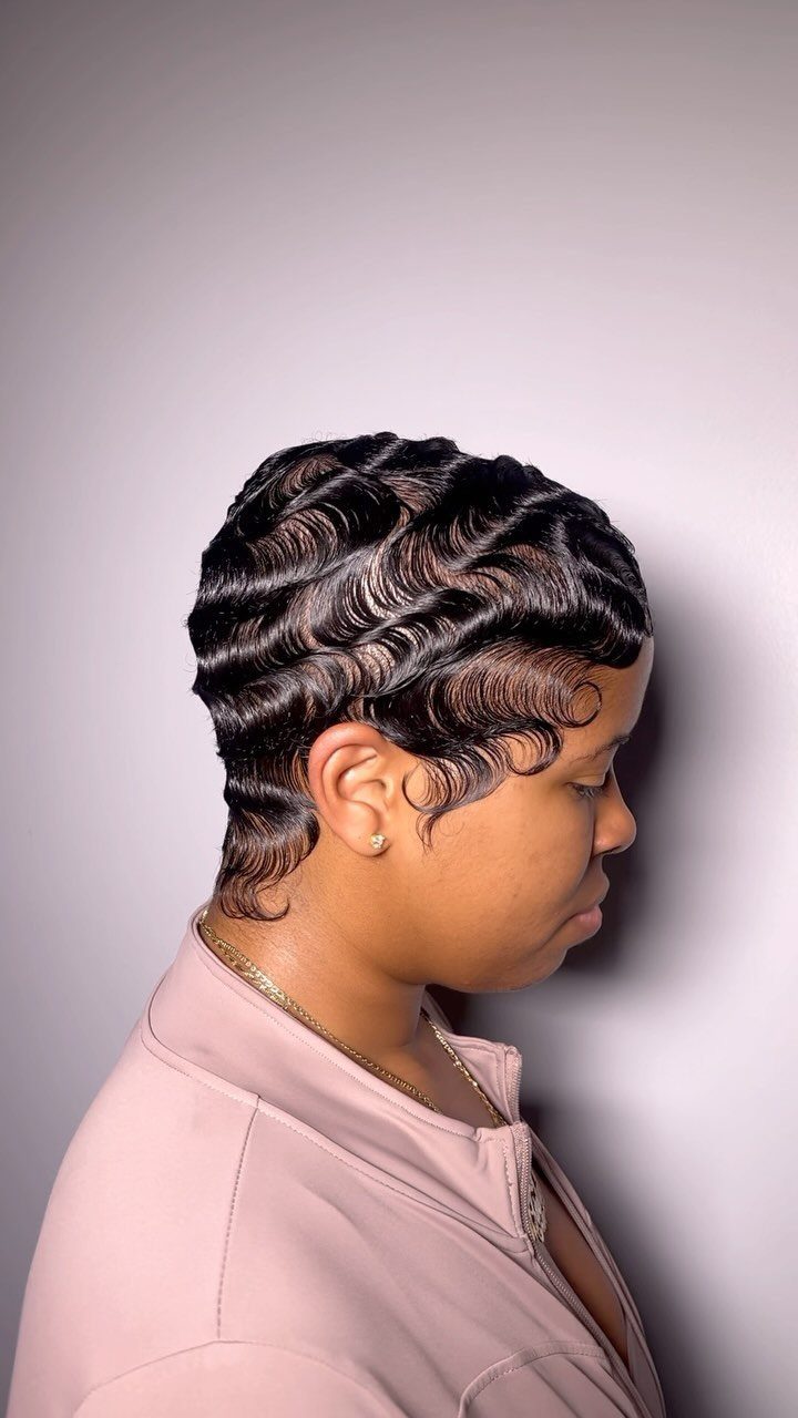Person with short black hair styled in glossy, sculpted gel waves side profile