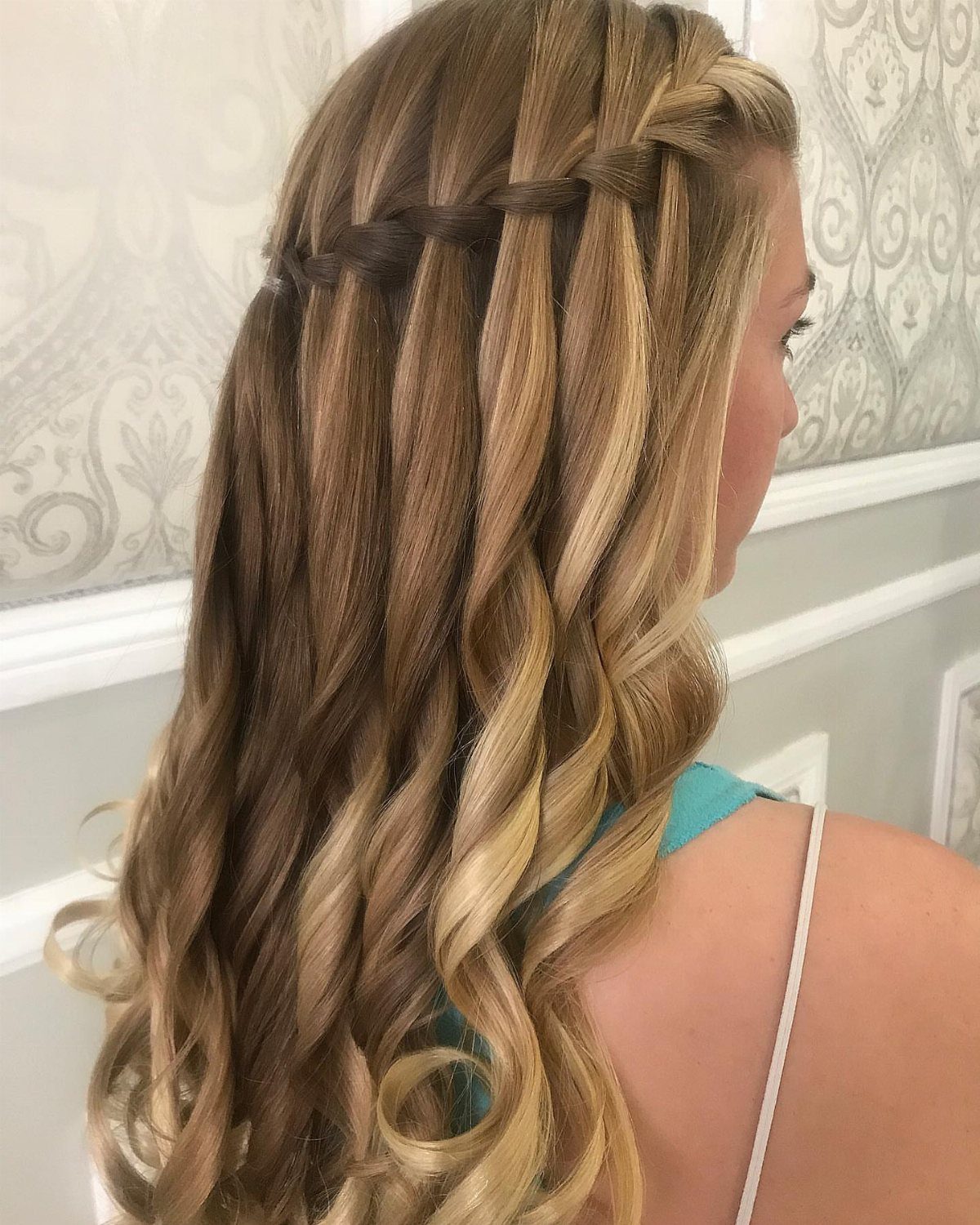 7 Half Braid Half Curly Hairstyles for Braids Mixed With Curls 4 Woman with blonde curly hair featuring a horizontal waterfall braid across the back.