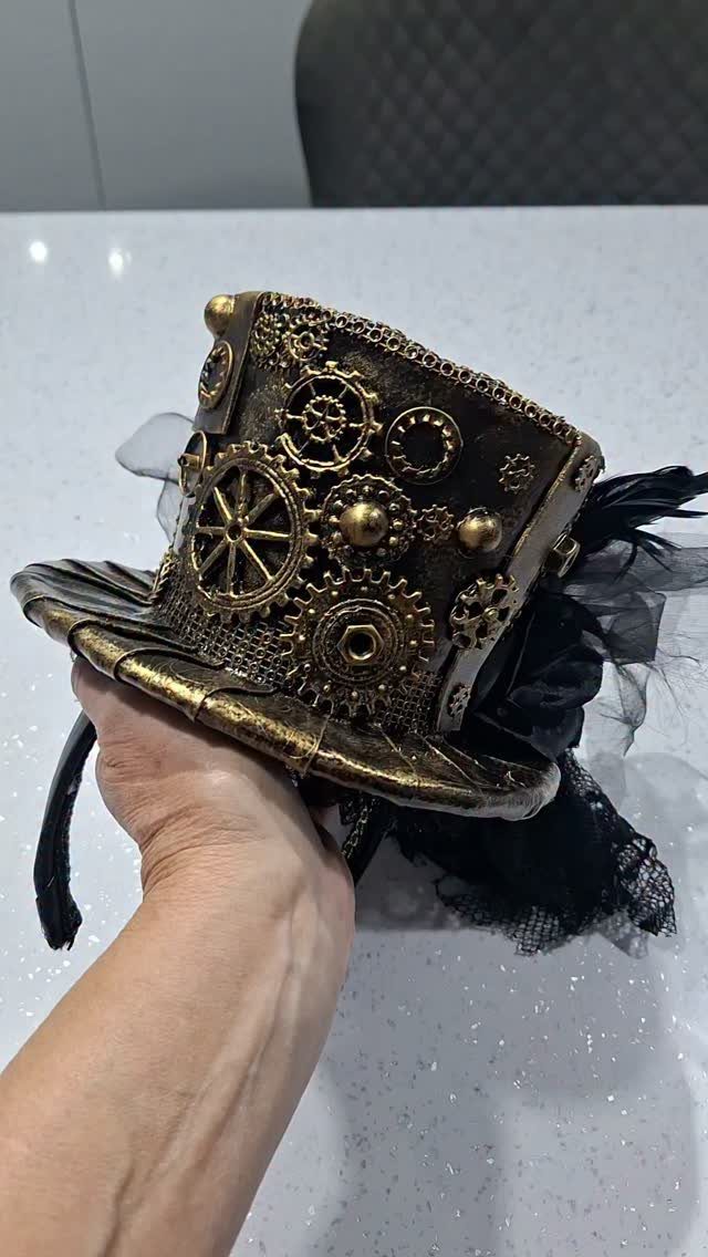 Mini gold steampunk top hat with metallic gears, black net veil, and feathers.