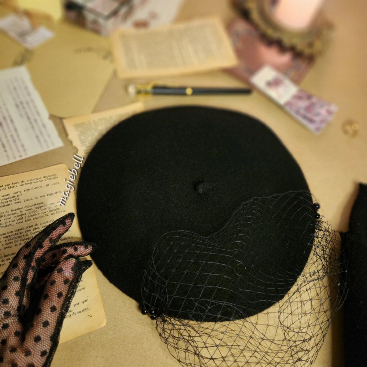 Black wool beret with a net veil on a vintage desk setting.