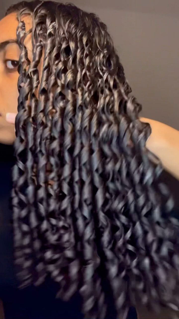 Long dark hair styled in tight, glossy, defined spiral curls.