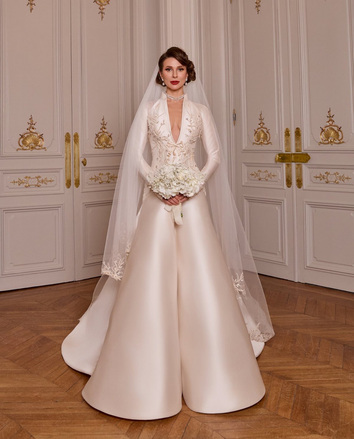 Woman in a long sleeve white satin ball dress holding a bridal bouquet