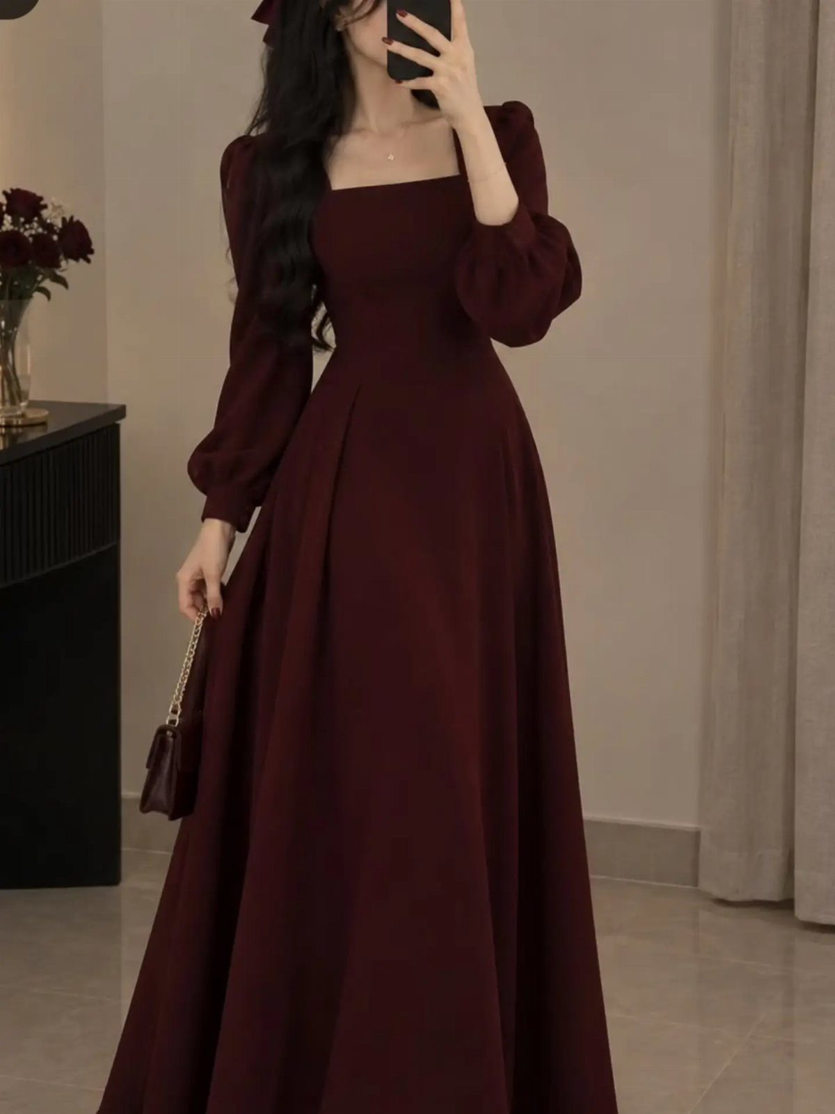 Burgundy long sleeve ball dress with a fitted bodice and full floor-length skirt.