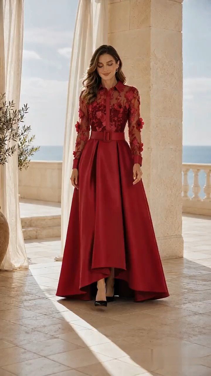 Woman in a red long sleeve ball dress standing on a sunny terrace.