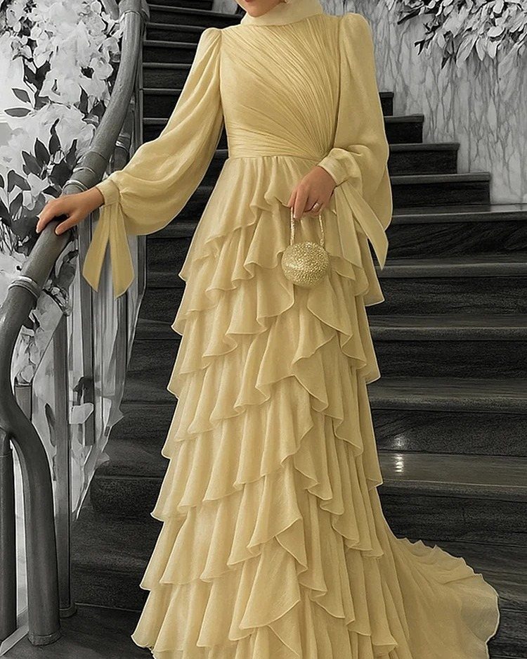 Pale yellow long sleeve ball dress with ruffled skirt on a staircase