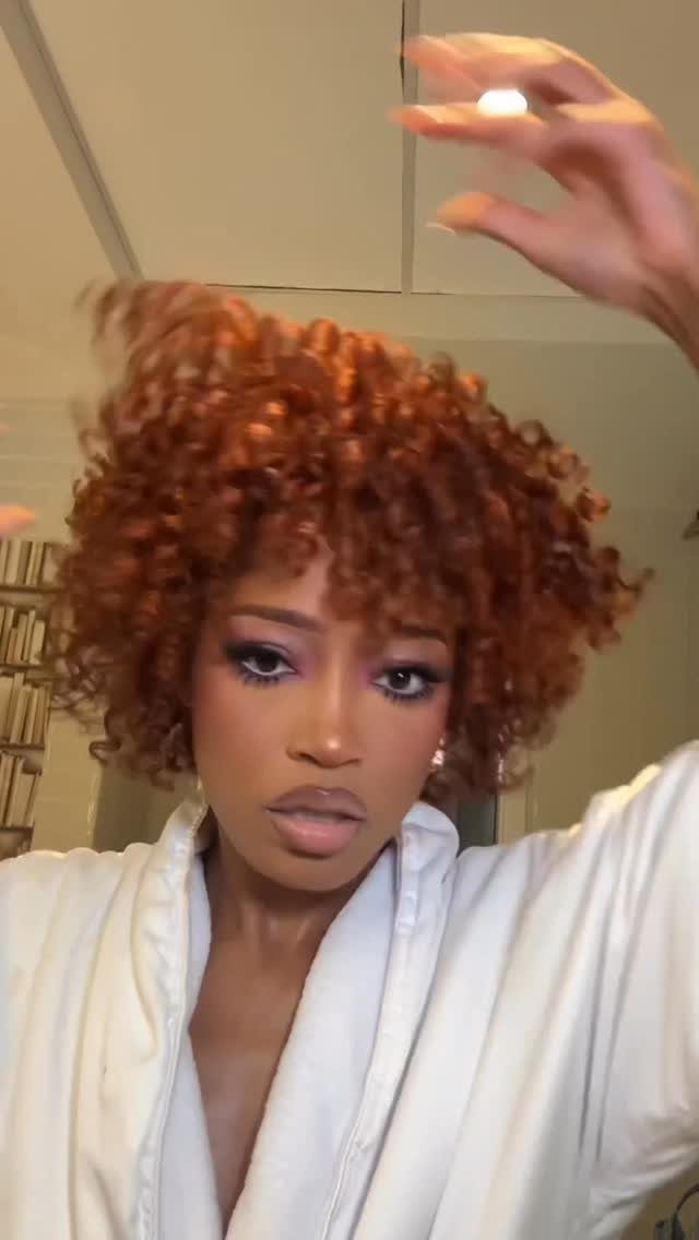 18 Medium Length Curly Hair Hairstyles, From Bobs to Shags 19 Woman with voluminous copper red curly hair wearing a white robe indoors.