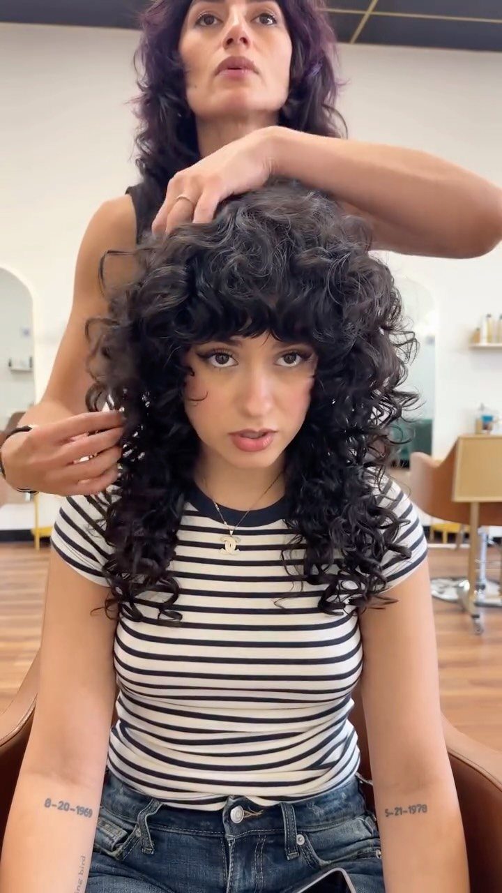 18 Medium Length Curly Hair Hairstyles, From Bobs to Shags 10 Woman with a voluminous curly shag haircut and bangs in a hair salon.