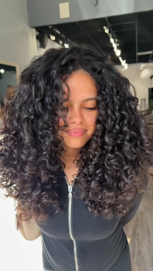 18 Medium Length Curly Hair Hairstyles, From Bobs to Shags 17 Woman with voluminous, defined black curly hair and long layers falling to shoulders.