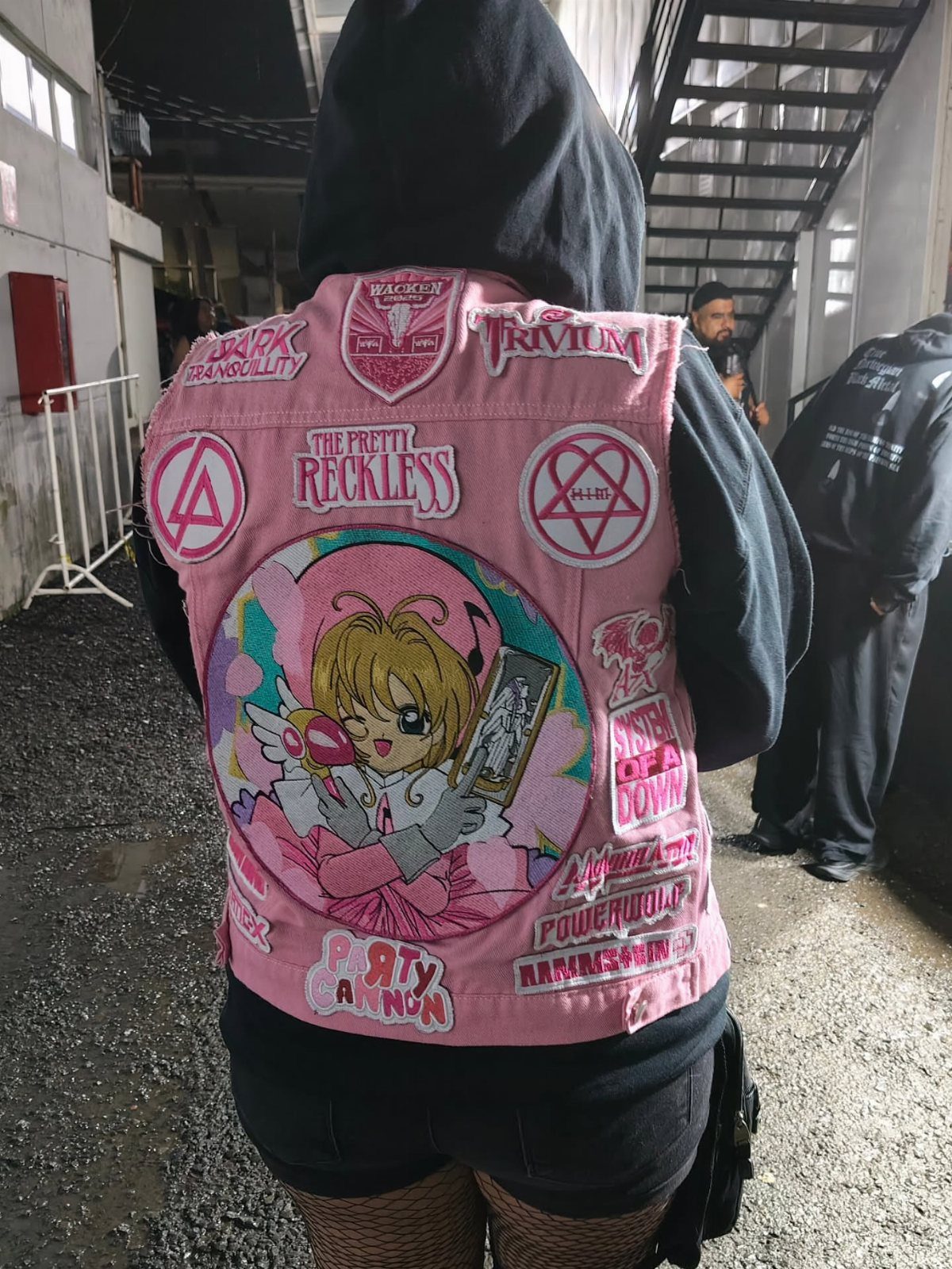 Metal Festival Outfit Ideas for Women: 10 Bold Looks to Try 7 Pink denim vest with band patches and anime art worn over black hoodie