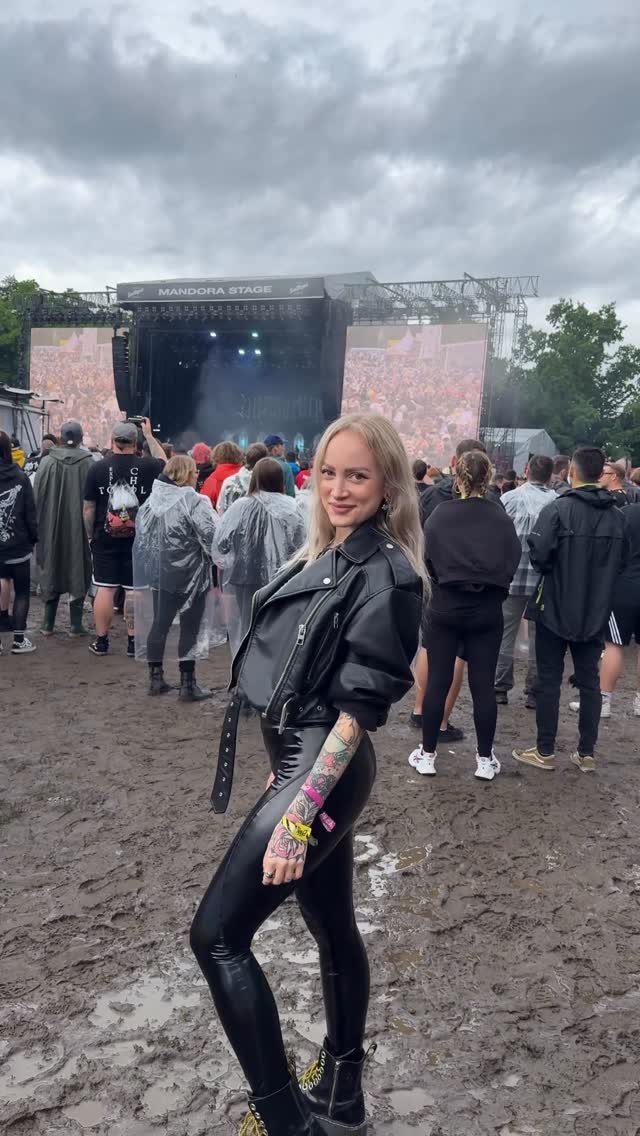 Metal Festival Outfit Ideas for Women: 10 Bold Looks to Try 9 Woman in black leather jacket and shiny leggings posing at a muddy music festival.