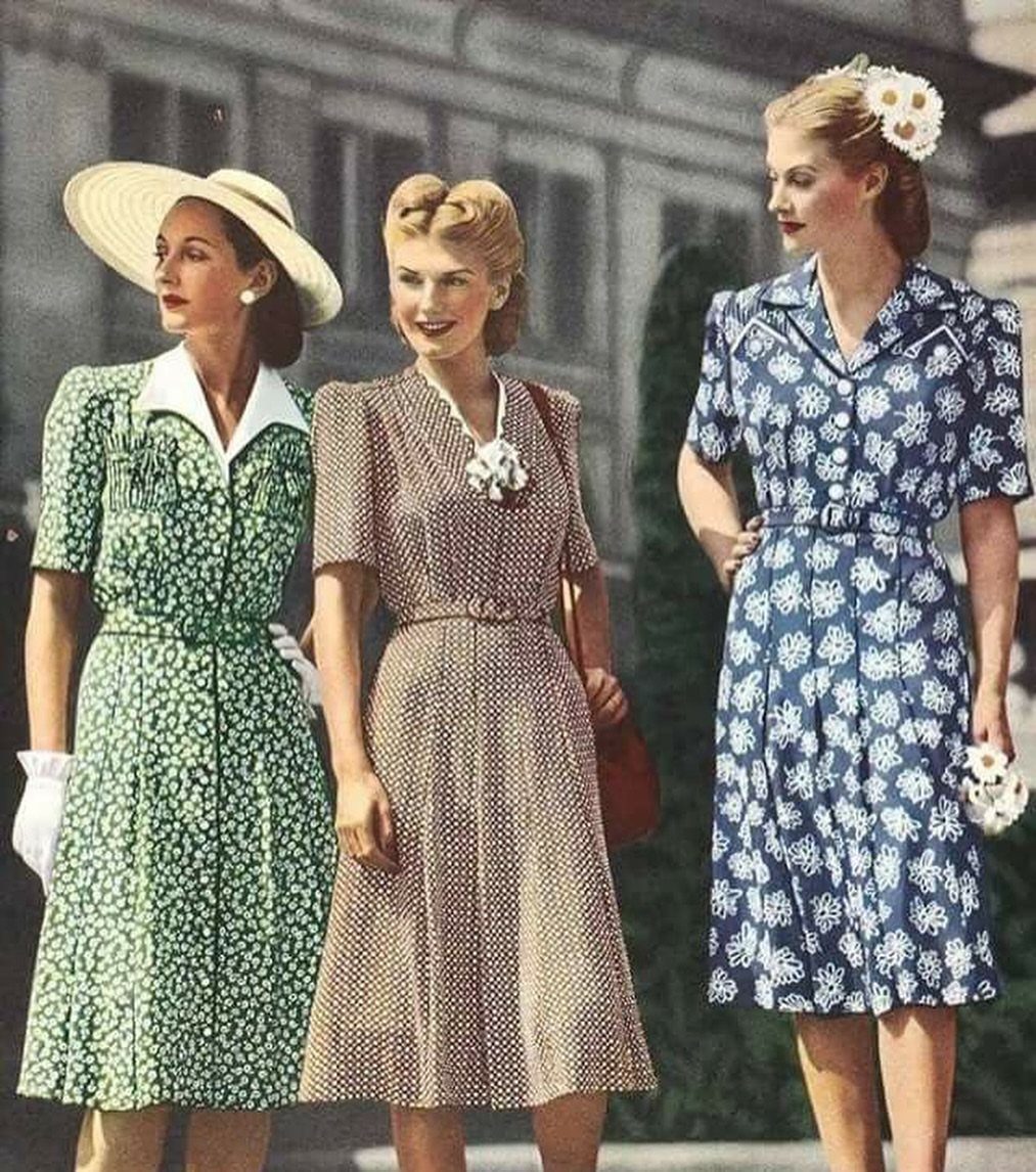 Three women wearing vintage floral dresses with cinched waists in green, brown, and blue.