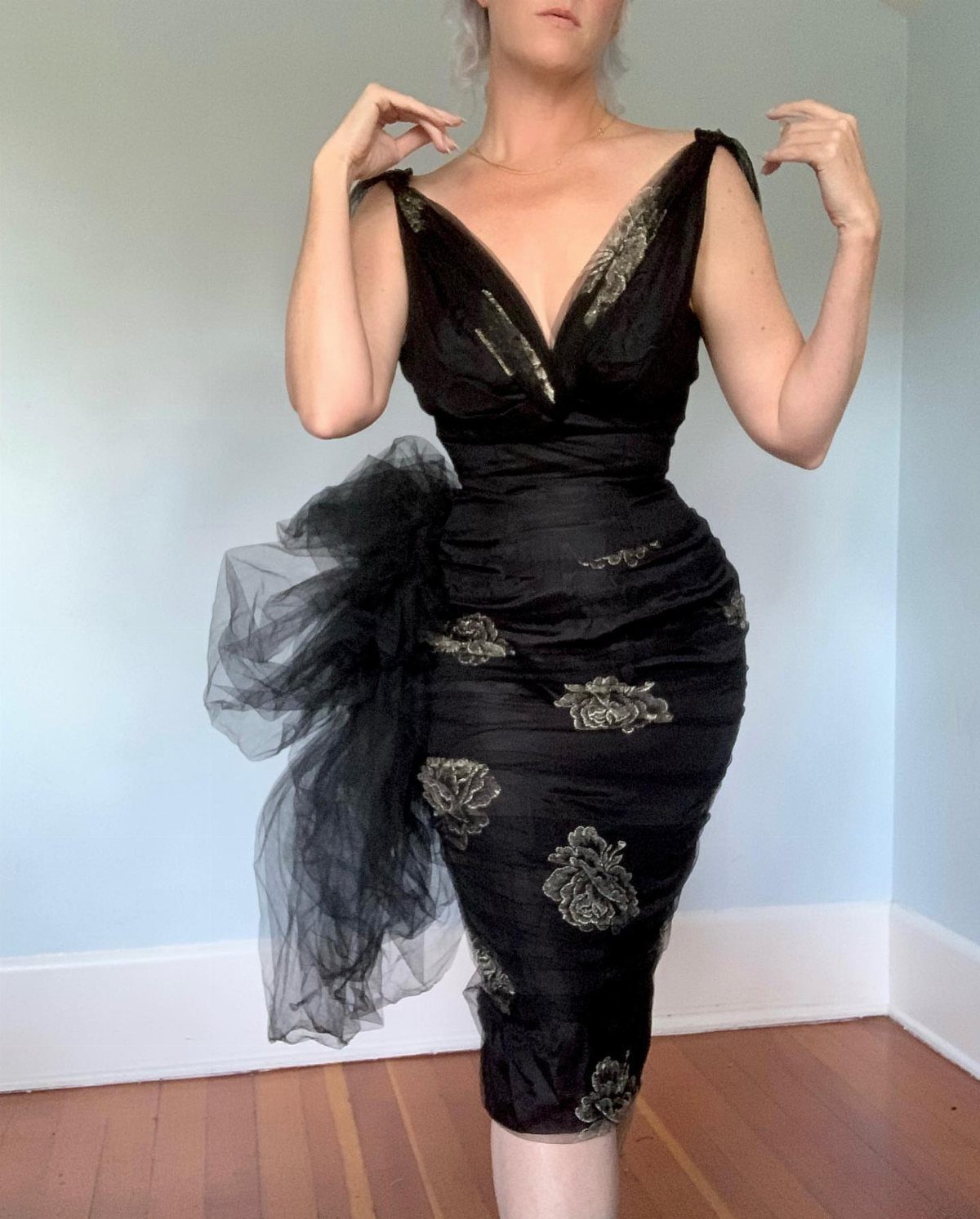 Black vintage evening dress with deep V-neck and gold floral embroidery on person