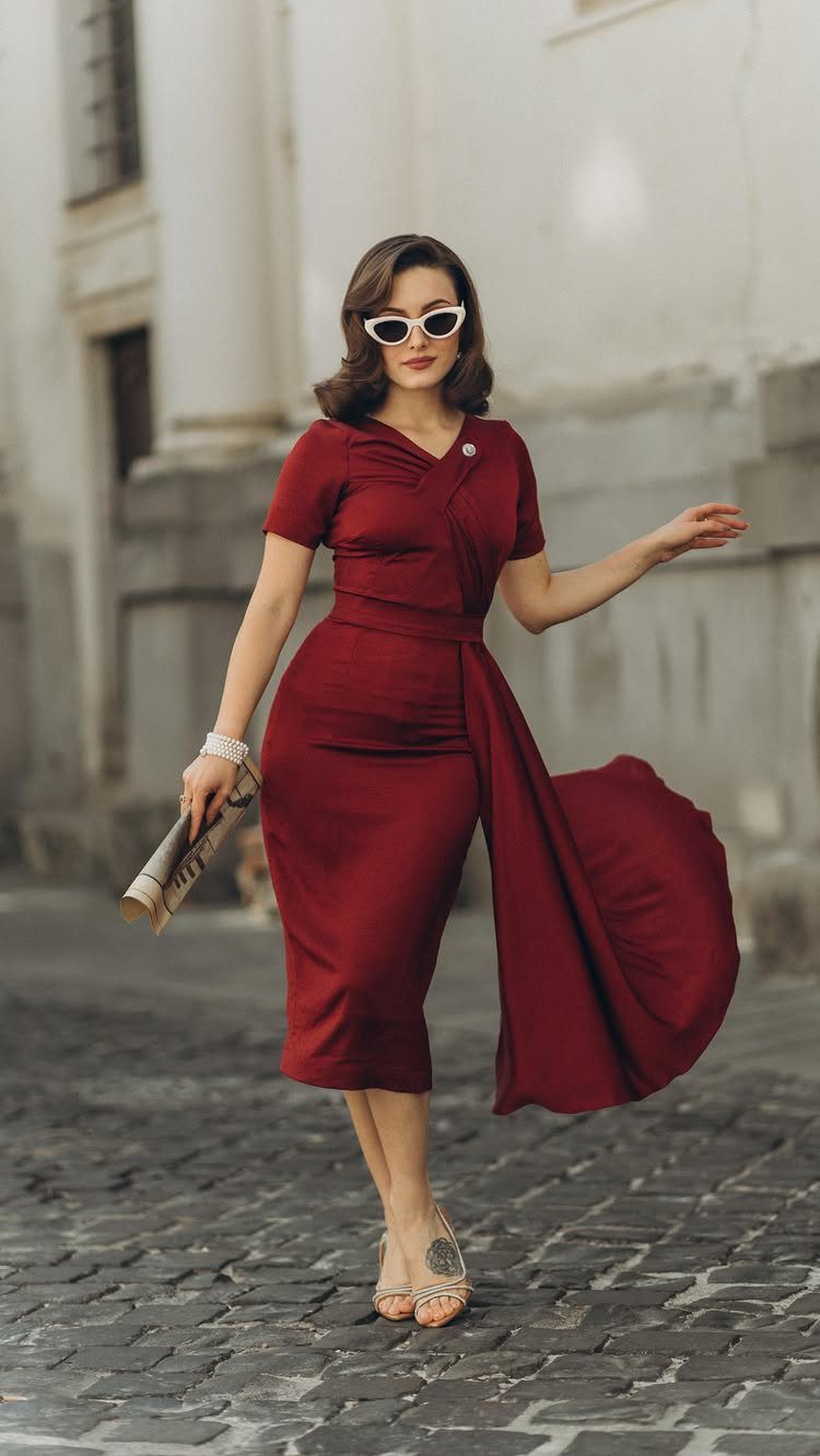 Woman in a vintage red midi dress and white cat-eye sunglasses on cobblestones