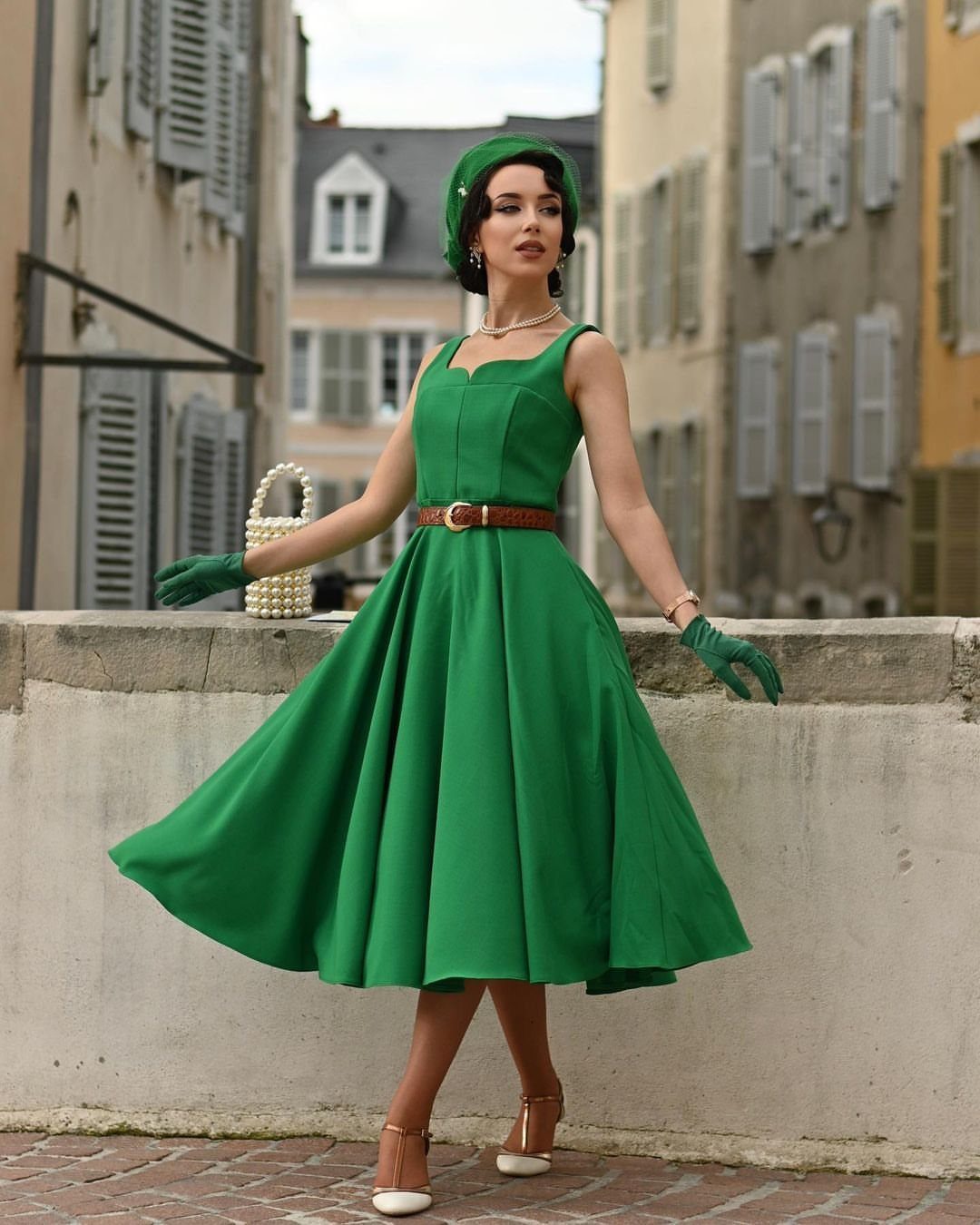 Woman in a green vintage scoop neckline dress and beret posing outdoors.