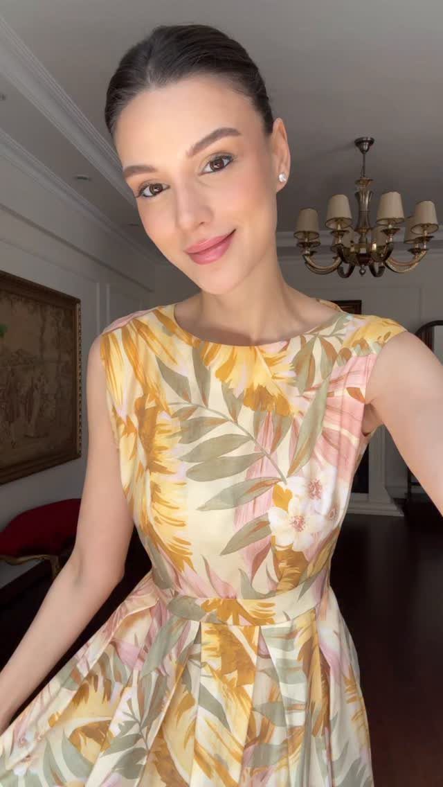 Woman wearing a short yellow and pink floral vintage style dress indoors.