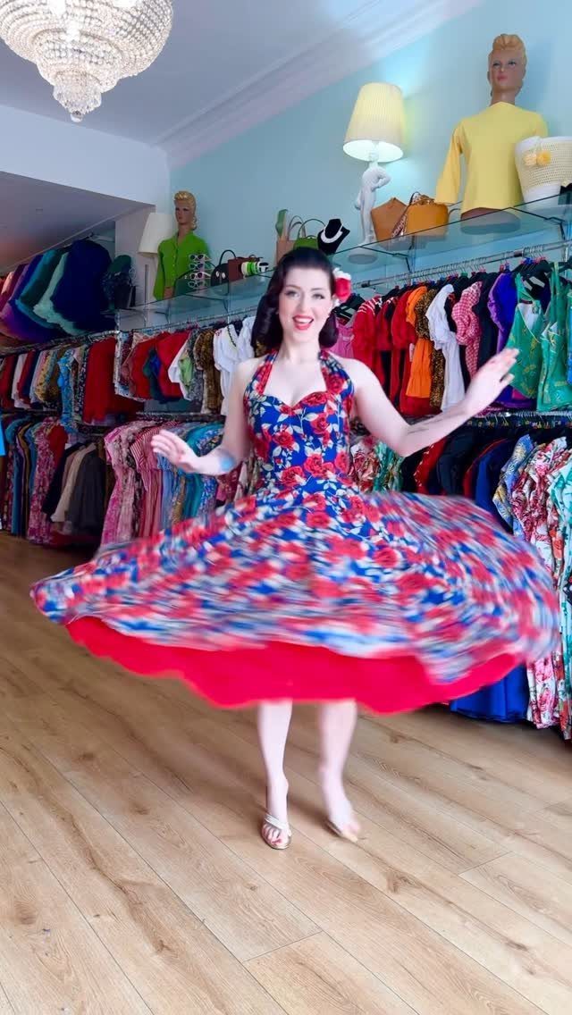 Woman spinning in a short red and blue floral vintage dress in a boutique.