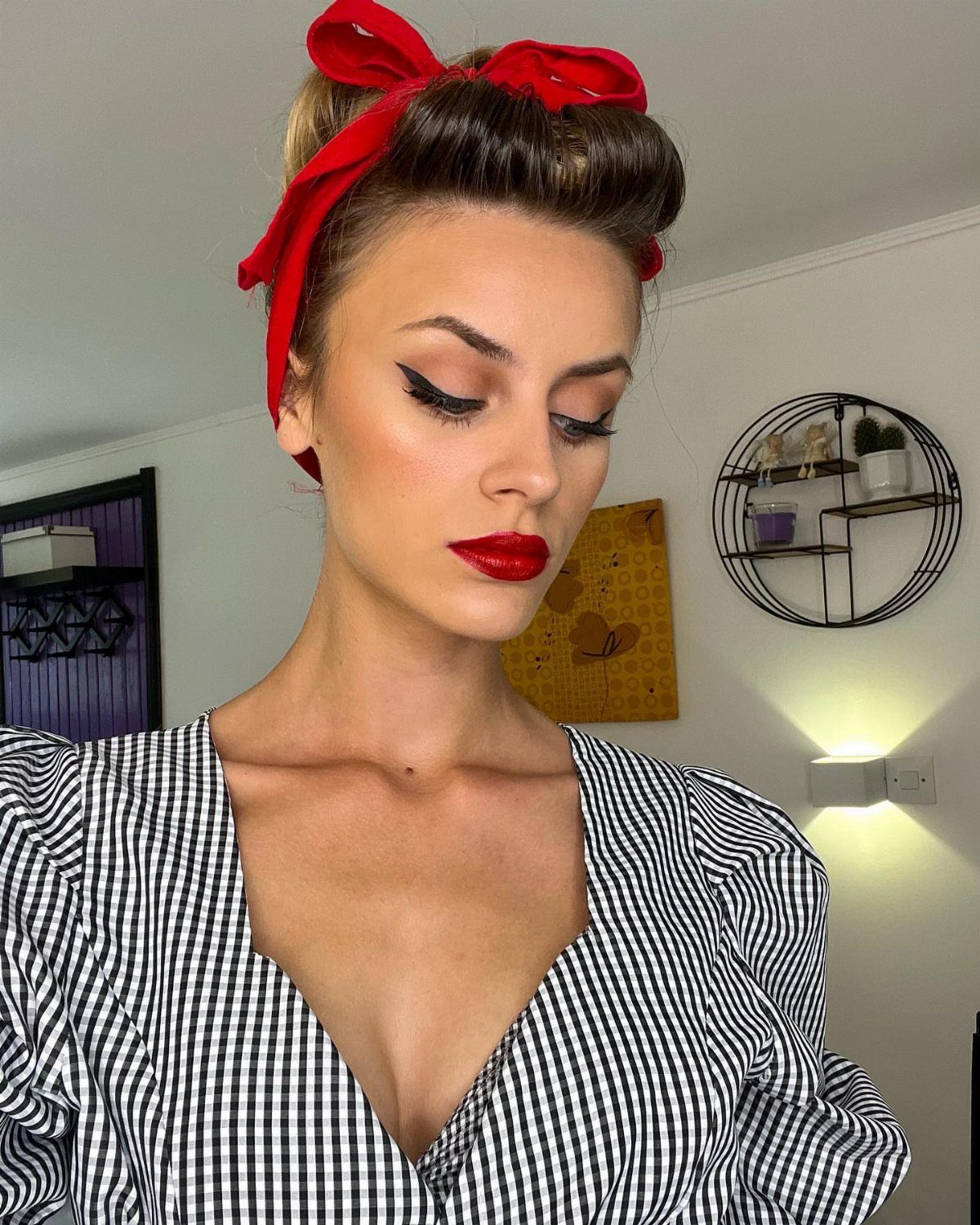 Pin Up Curls Hairstyles: 7 Ideas From Victory Rolls to Bows 6 Woman with vintage victory roll hairstyle, red bow headband, and checkered dress.