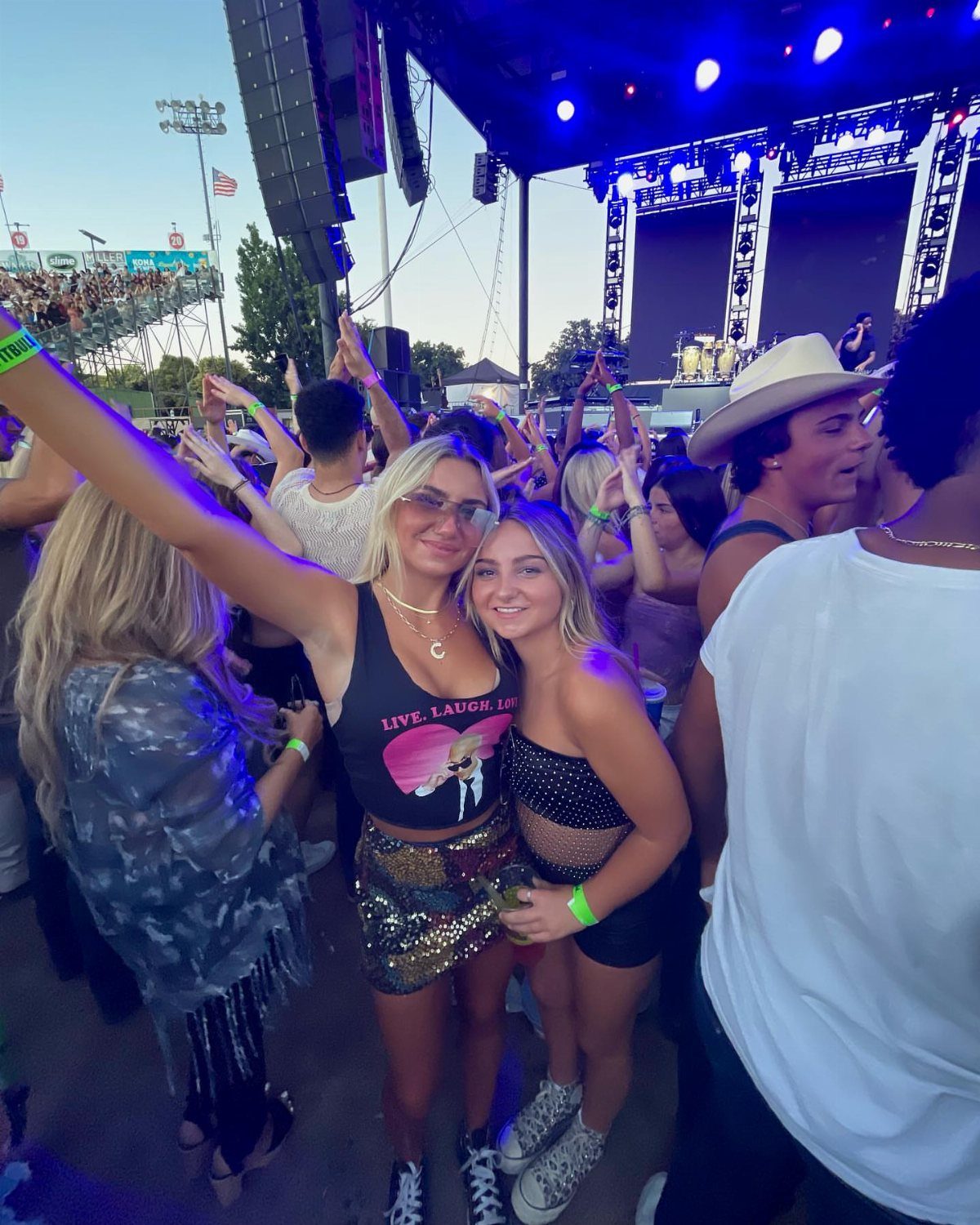 Two women posing at a concert, one wearing a gold sequined mini skirt.