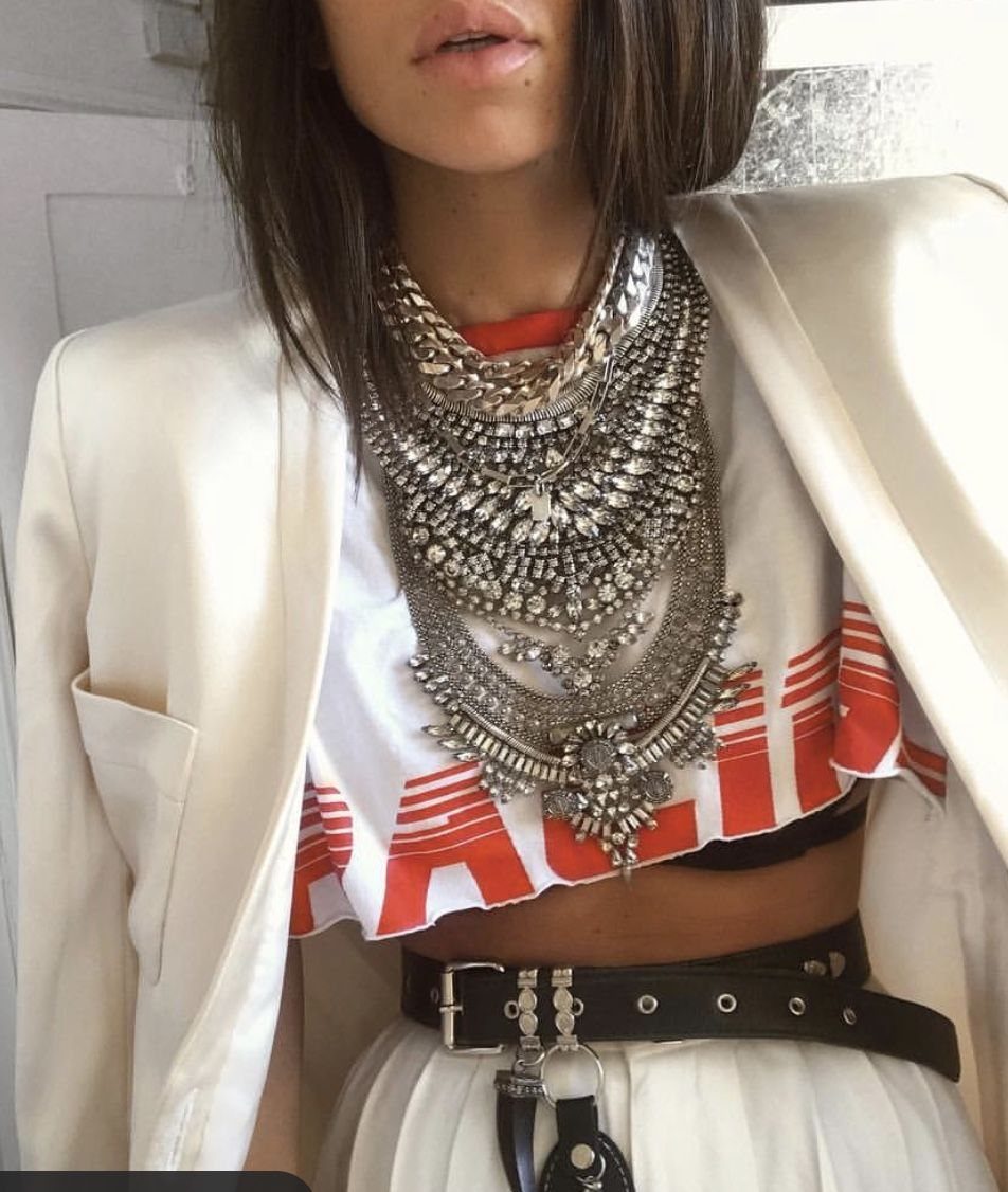 Layered silver statement necklace worn over a white and red graphic crop top.