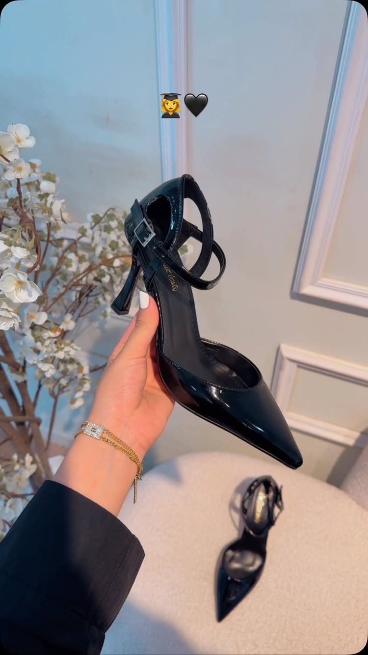 Black patent leather high-heeled pumps with pointed toes and ankle straps.