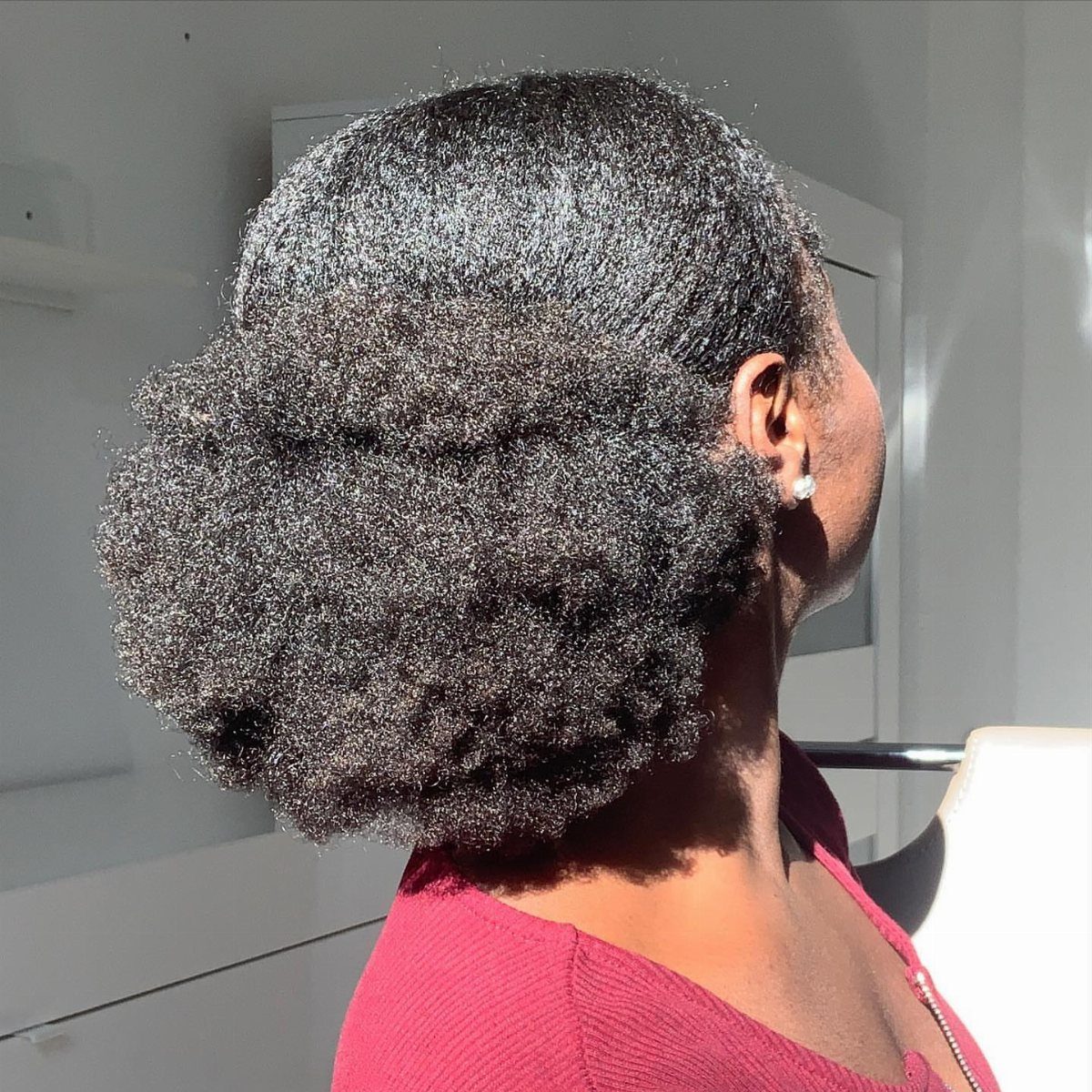 Woman with dark curly hair styled into a large back-gathered puff hairstyle.