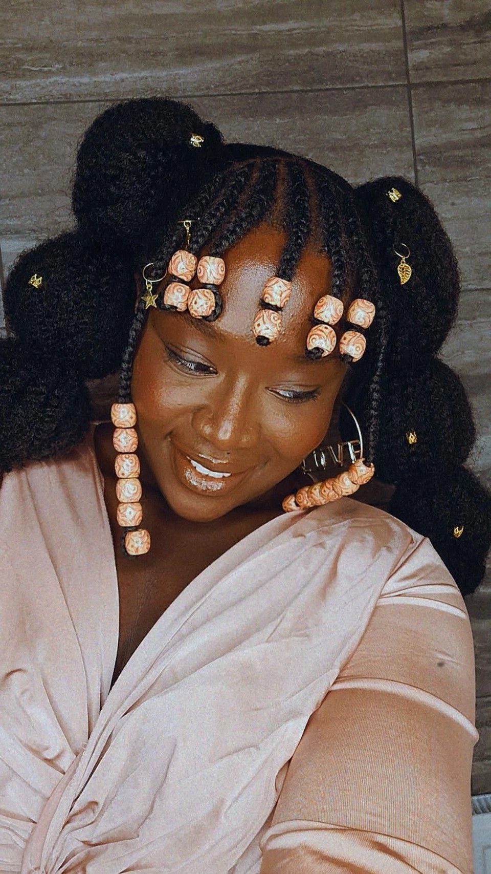 Woman with afro puffs and braids decorated with light-colored patterned beads.