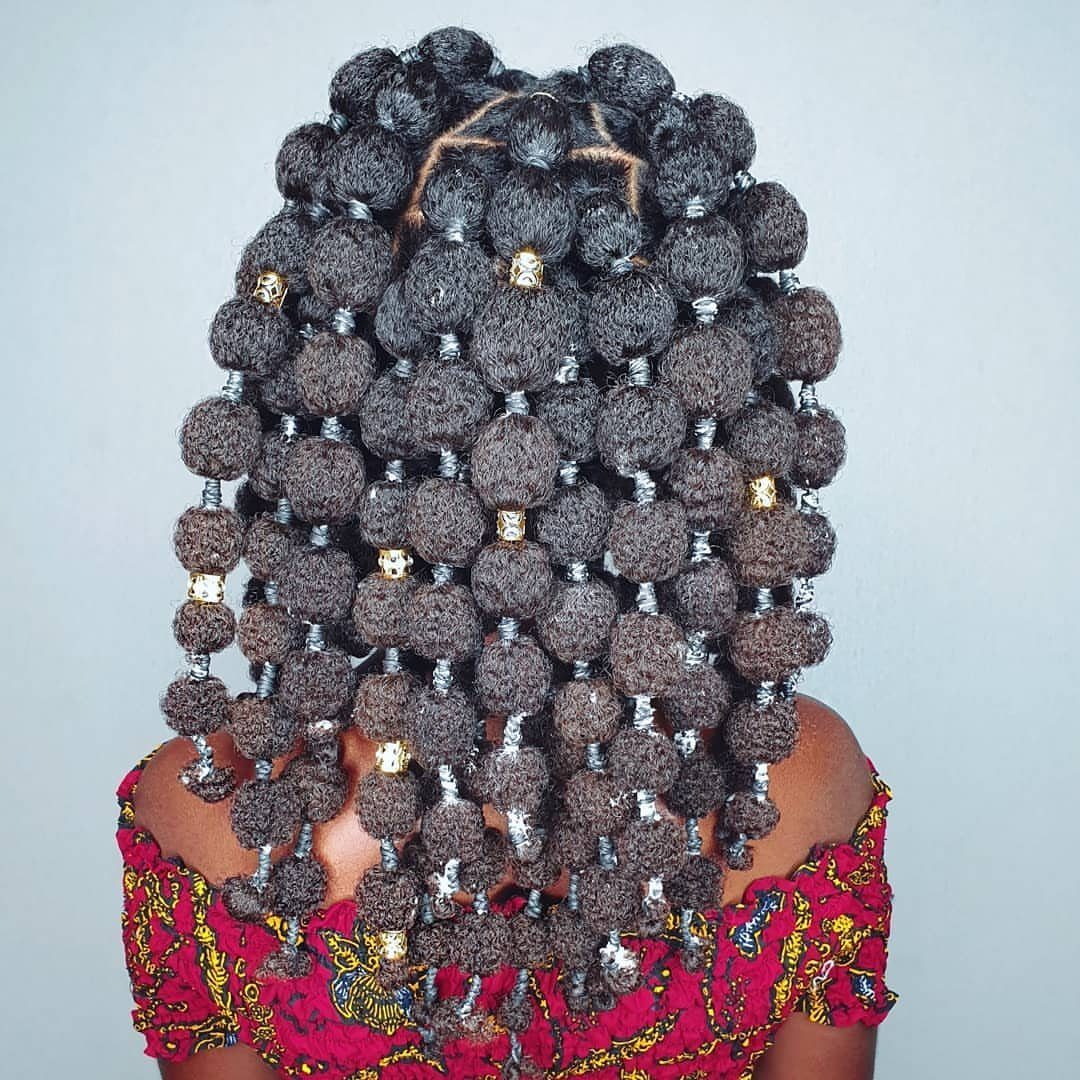 Back view of coiled hair puffs decorated with gold metallic hair cuffs.