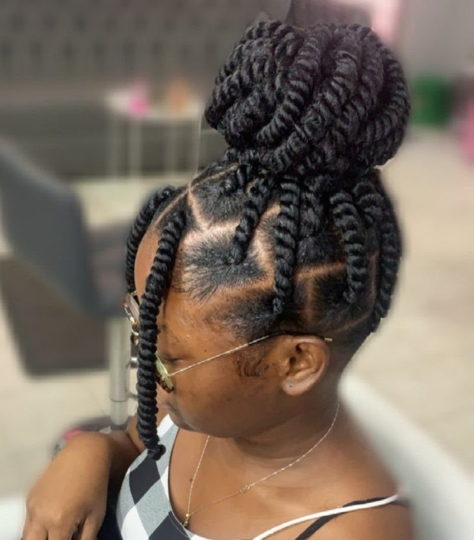 Woman with two-strand twists gathered into a high, voluminous puff bun hairstyle.