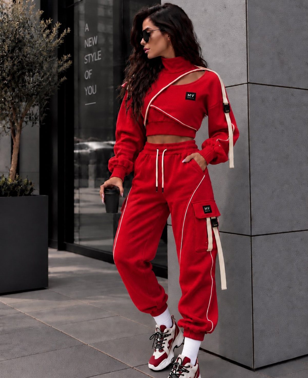 Woman in red cropped long-sleeve top and matching red track pants with sneakers.